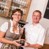 Bild anzeigen: Herr und Frau Greilinger halten Weinflasche