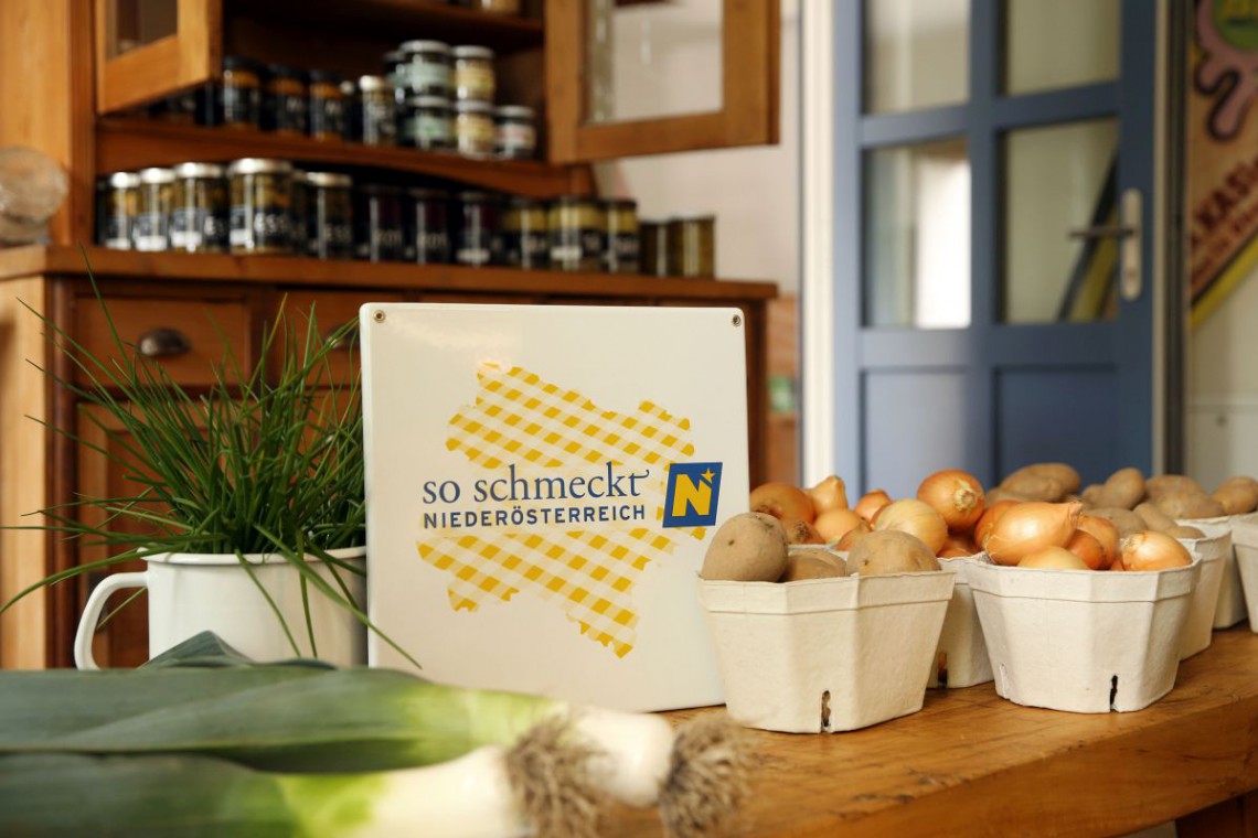Milchkasino Tisch mit Zwiebeln, Erdäpfeln, Lauch und Schnittlauch und der So-Schmeckt-Niederösterreich-Plakette 