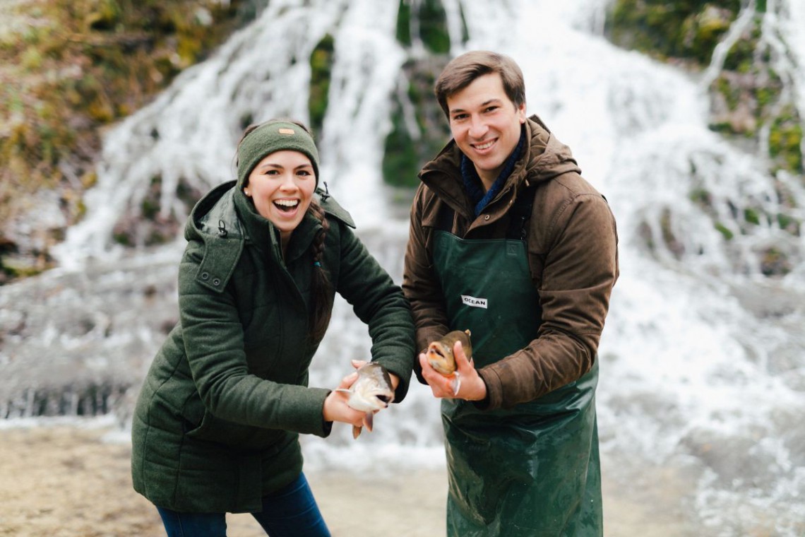 Thorhof Marlene und Christian Kirchmayer vor Wasserfall mit Fisch in der Hand