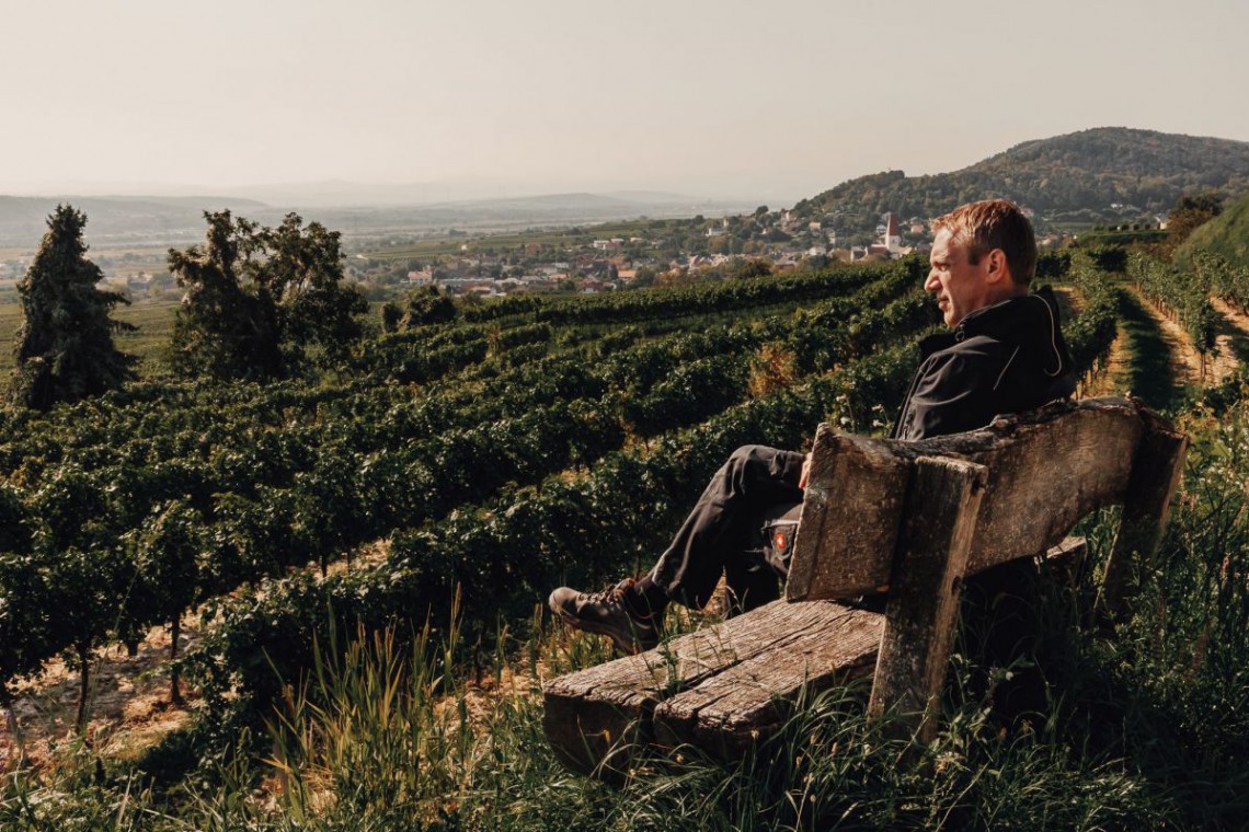 
Obsthof Altenriederer, Herr Altenriederer sitzt auf Bank mit Blick über das Traisental
