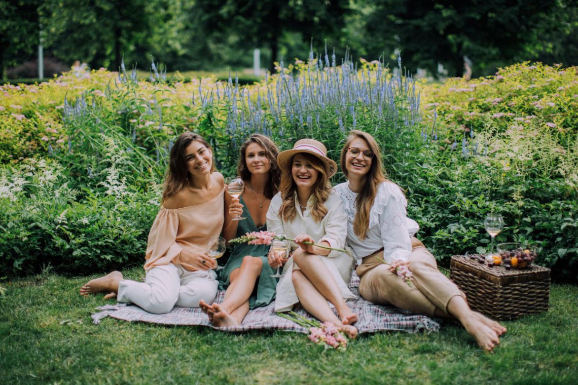 4 Frauen sitzen auf Wiese und trinken Sekt