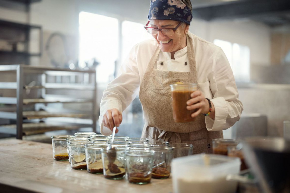 Frau f&uuml;llt Essen in Gl&auml;ser ein