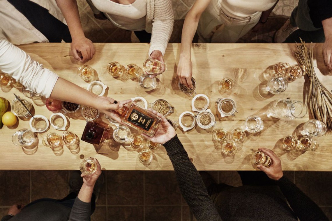 Vogelperspektive, Menschen sitzen an Tisch und schenken sich Whisky ein