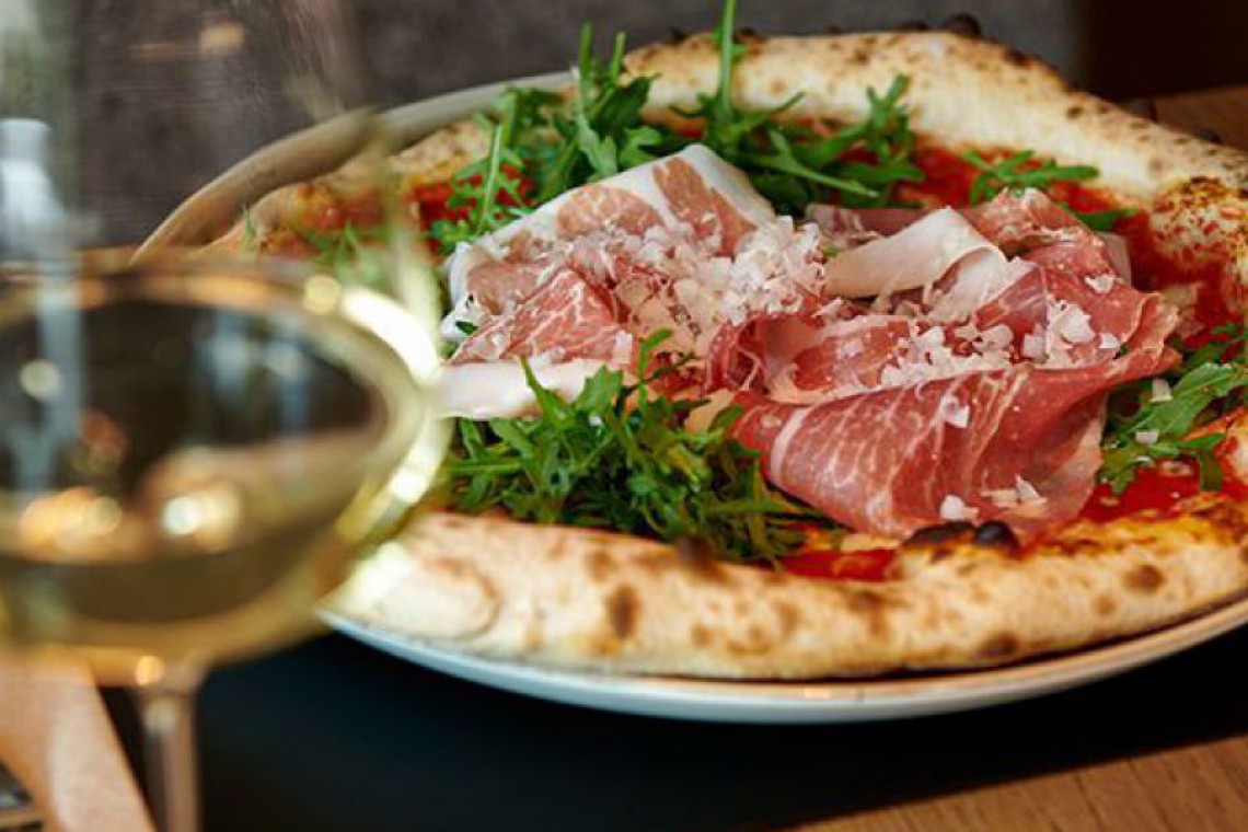 Auf eine Pizza wird Parmesan gerieben