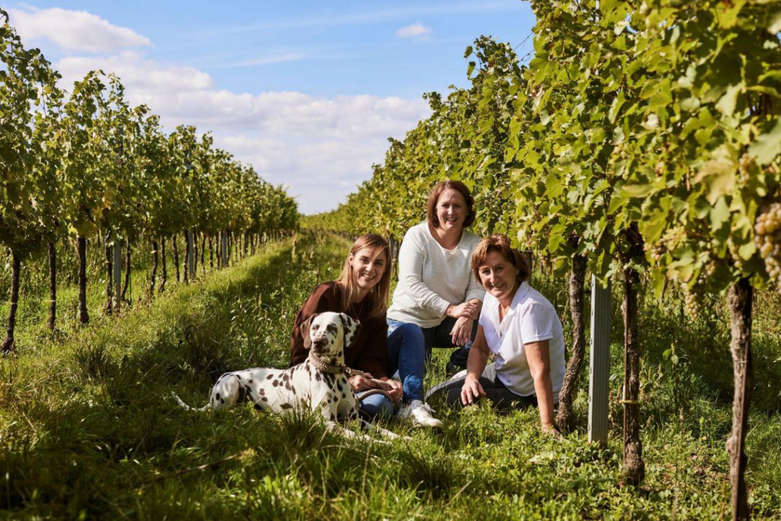 Kerstin und Nadine Schüller mit ihrer Mutter und ihrem Hund sitzen in den Weingärten. 