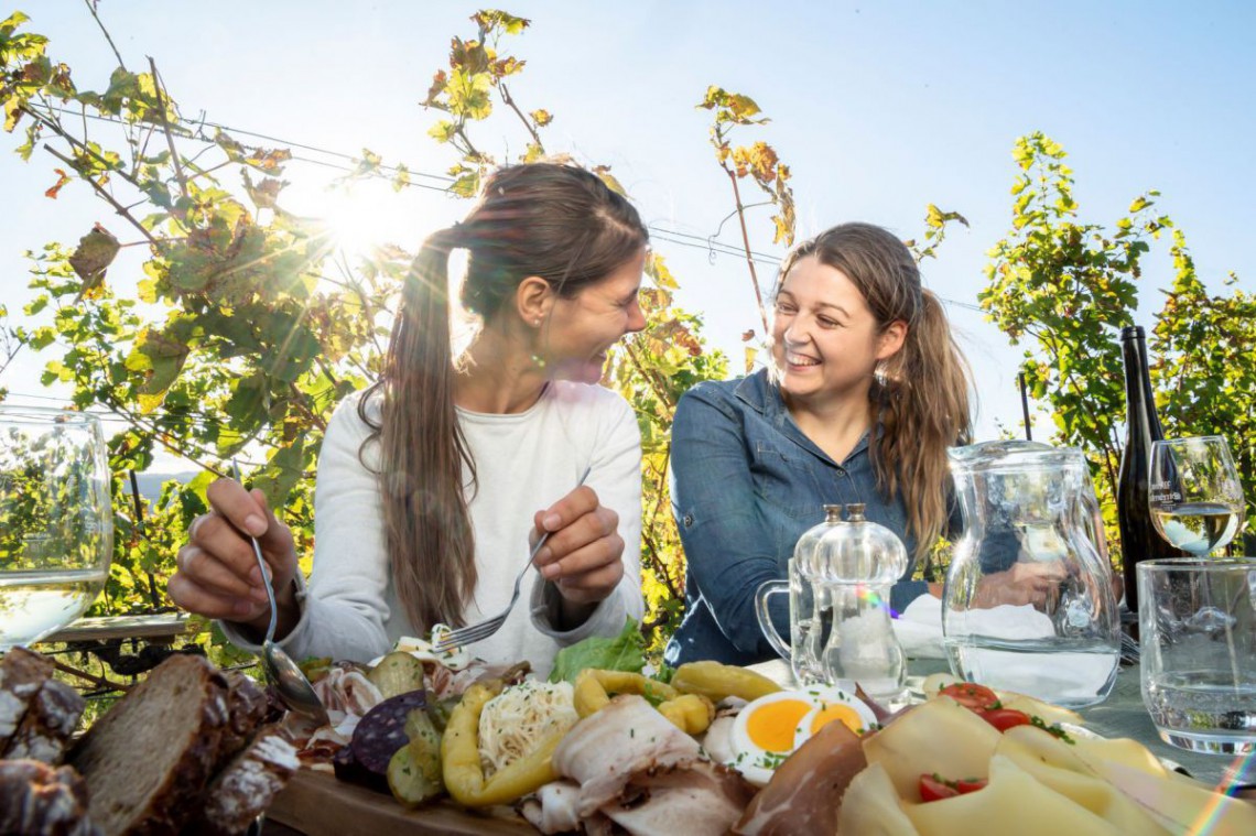 2 Frauen sitzen am Tisch und essen typische Heurigen-Jause