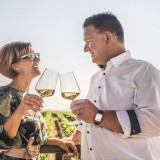 Bild anzeigen: Bioweingut Urbanihof, Frau und Herr Paschinger im Weingarten mit Weinglas