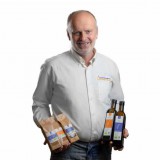 Bild anzeigen: Schwarzinger Öle, Herr Schwarzinger mit Ölflaschen und Ölsaatenpackungen in der Hand
