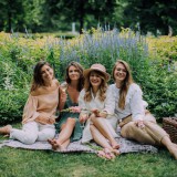 Bild anzeigen: 4 Frauen sitzen auf Wiese und trinken Sekt