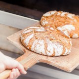 Bild anzeigen: Zwei Laib Brot die gerade in den Ofen geschoben werden