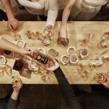 Bild anzeigen: Vogelperspektive, Menschen sitzen an Tisch und schenken sich Whisky ein