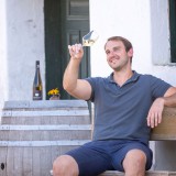 Bild anzeigen: Herr F&uuml;rnkranz auf einer Bank schaut ein Glas Wein an