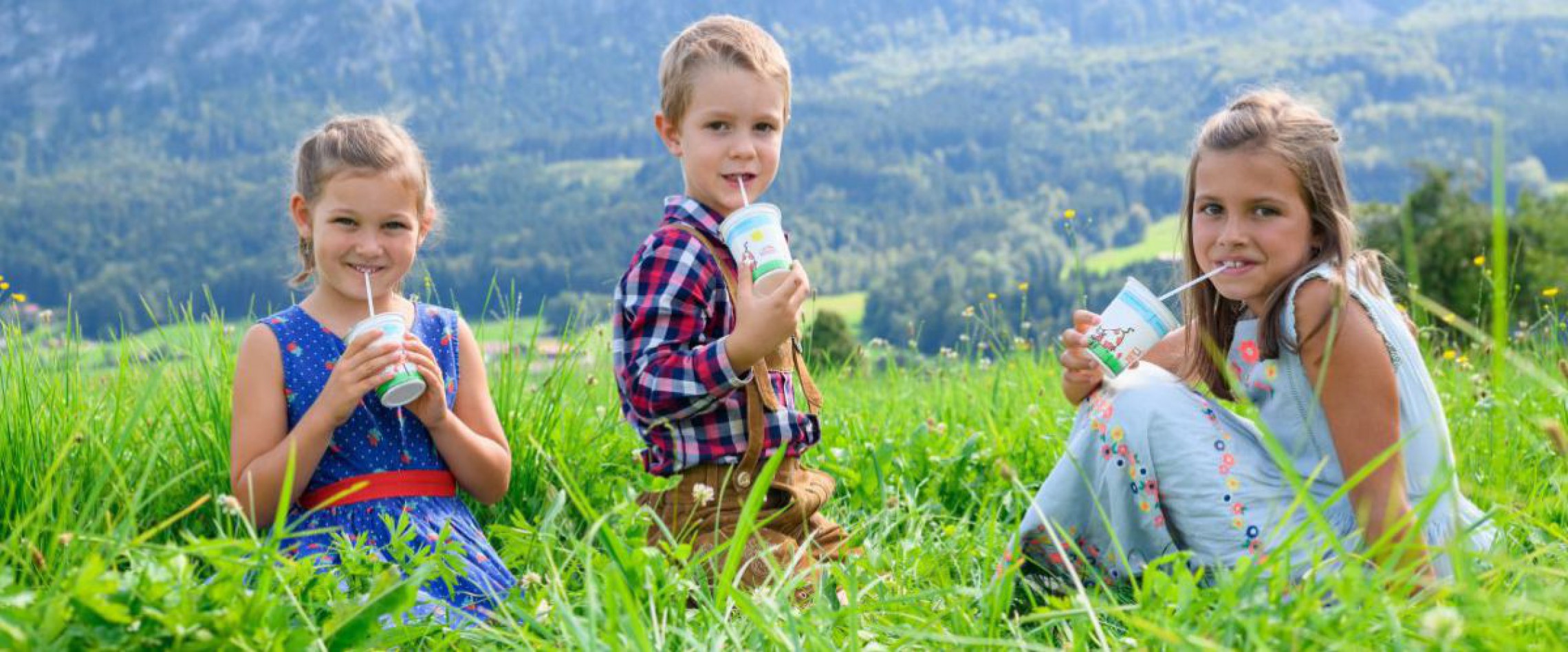 Kinder im Gras mit Schulmilch in der Hand