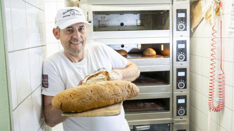 Bäckermeister Schuh in seiner Backstube mit einem Laibbrot