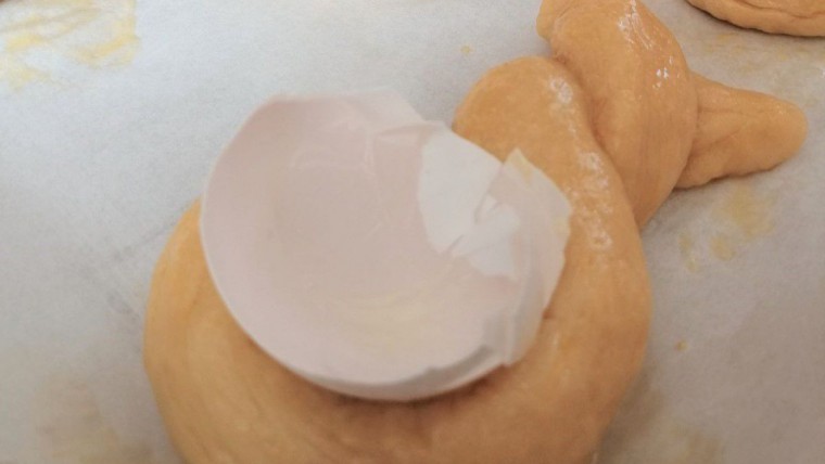 eine halbe Eierschale auf dem Germteig-Osterhasen vor dem Backen