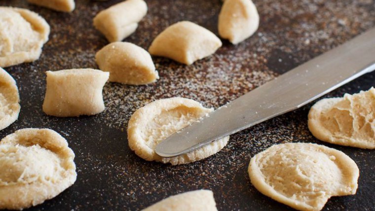 Nudelteig, der vorportioniert wird und von kleinen Stücken per Messer zu Muscheln gedrückt wird