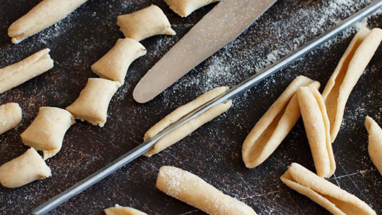 Nudelteig, der vorportioniert wurde und nun über einen metallenen Spieß geformt wird