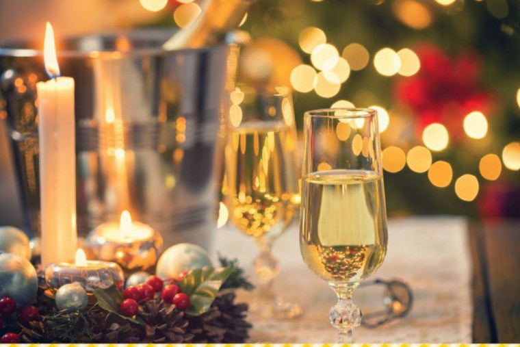 Ein Glas Sekt steht auf einem weihnachtlich dekorierten Tisch