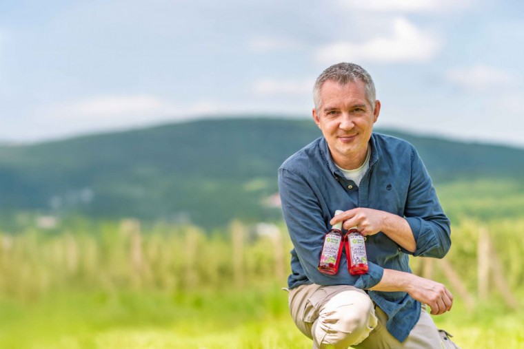 Michael Priessnitz im Feld mit 2 Flaschen Sirup in der Hand
