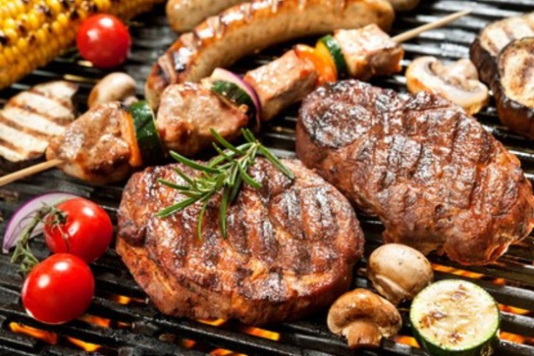 Mit Kräutern gewürztes Fleisch und Gemüse auf einem Grillrost 