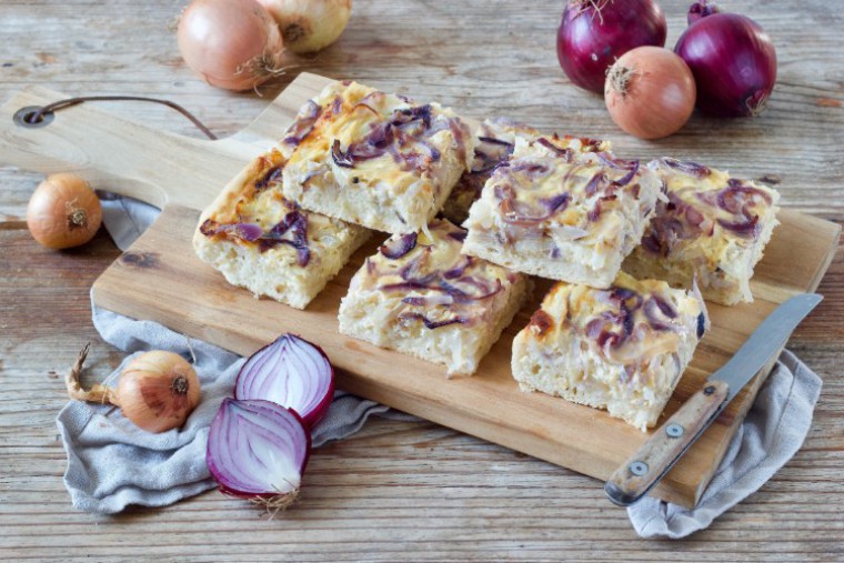 Zwiebelkuchen aufgeschnitten auf Holzbrett