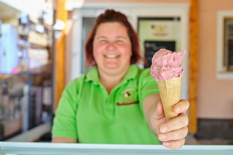 Dame mit Eis in der Hand, das sie über die Theke reicht. 