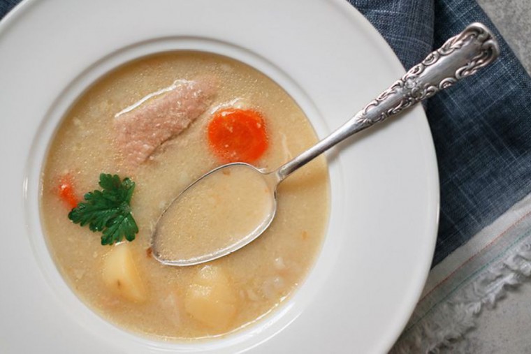 Rahmsuppe mit Schweinefleisch und Wurzelgemüse, angerichtet in einem Suppenteller