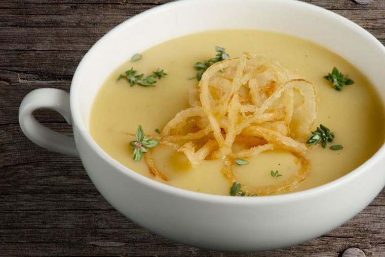 Cremesuppe in einem Suppenteller angerichtet, getoppt mit gebratenen Zwiebelringen