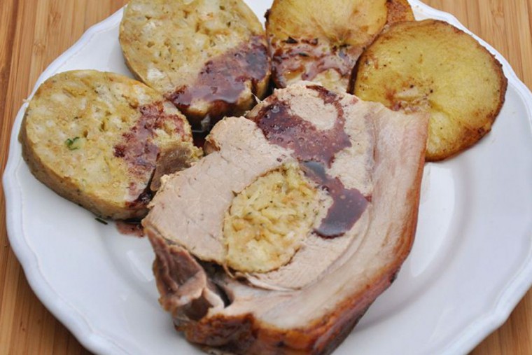 Ein Stück Schweinsbraten auf einem Teller mit Kartoffeln als Beilage