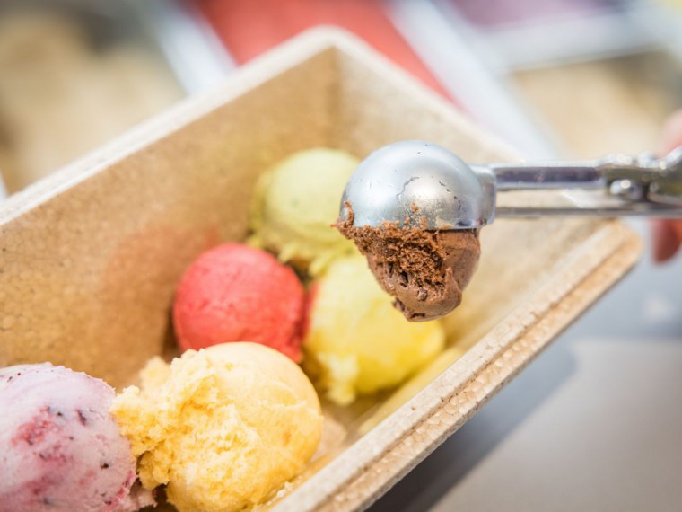 Eisverk&auml;uferin f&uuml;llt verschiedene Sorten Eiskugeln in eine K&uuml;hlbox.