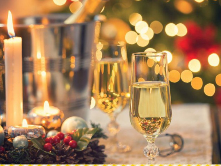 Ein Glas Sekt steht auf einem weihnachtlich dekorierten Tisch