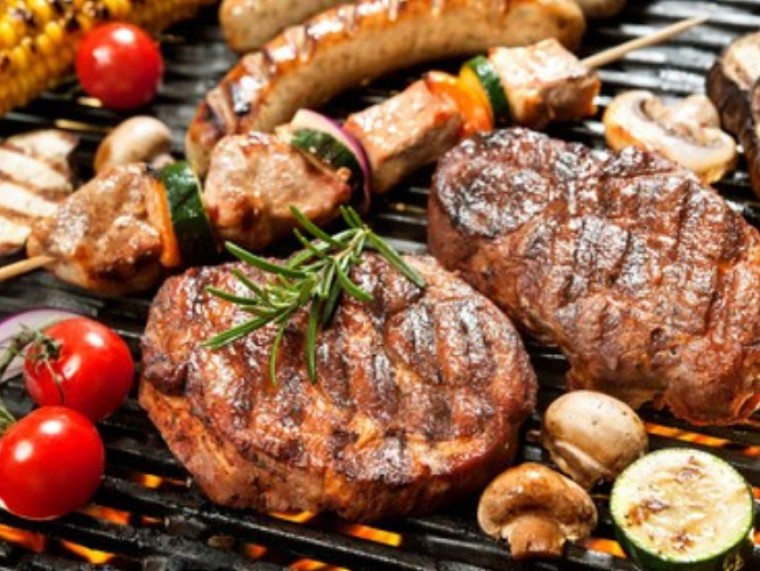 Mit Kräutern gewürztes Fleisch und Gemüse auf einem Grillrost 