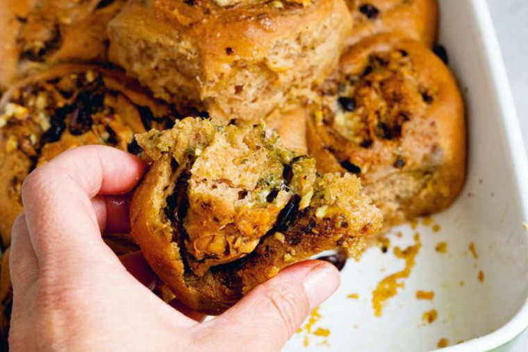 Eine Hand, die sich eine Brotschnecke vom Zupfbrot schnappt